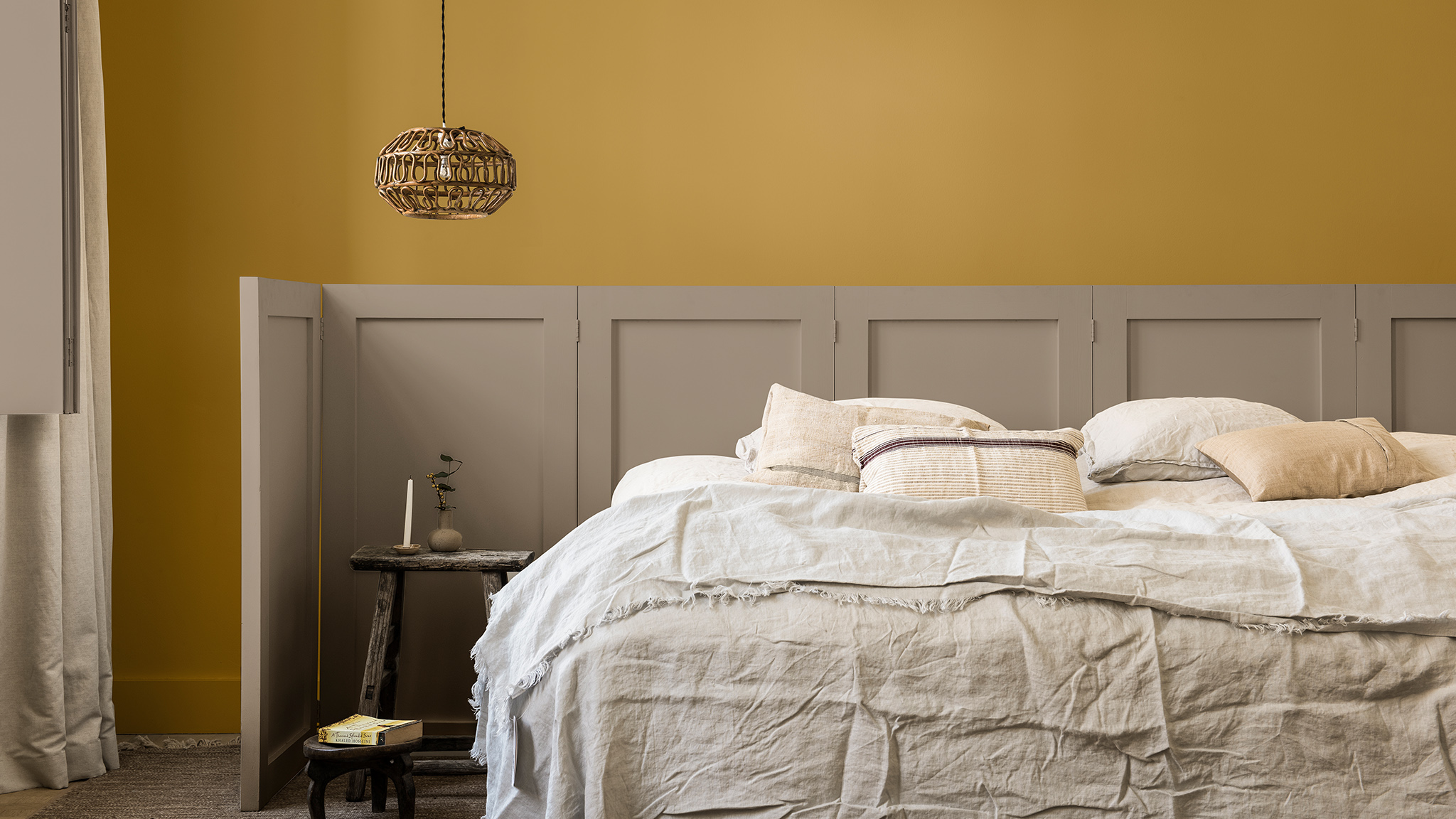 Mur de chambre en jaune doré et Brave Ground avec paravent lambrissé derrière le lit Dulux_CF21_ Colour_of_the_year_Timeless_colors_global_2