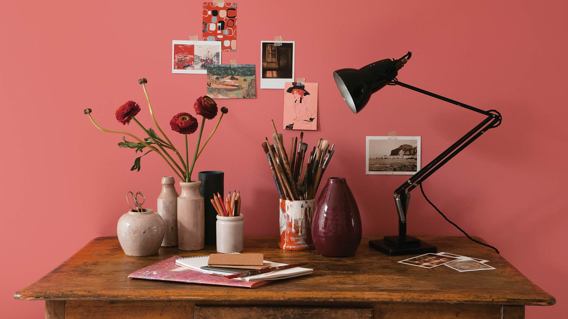 Bureau en bois et cartes postales sur un mur rouge